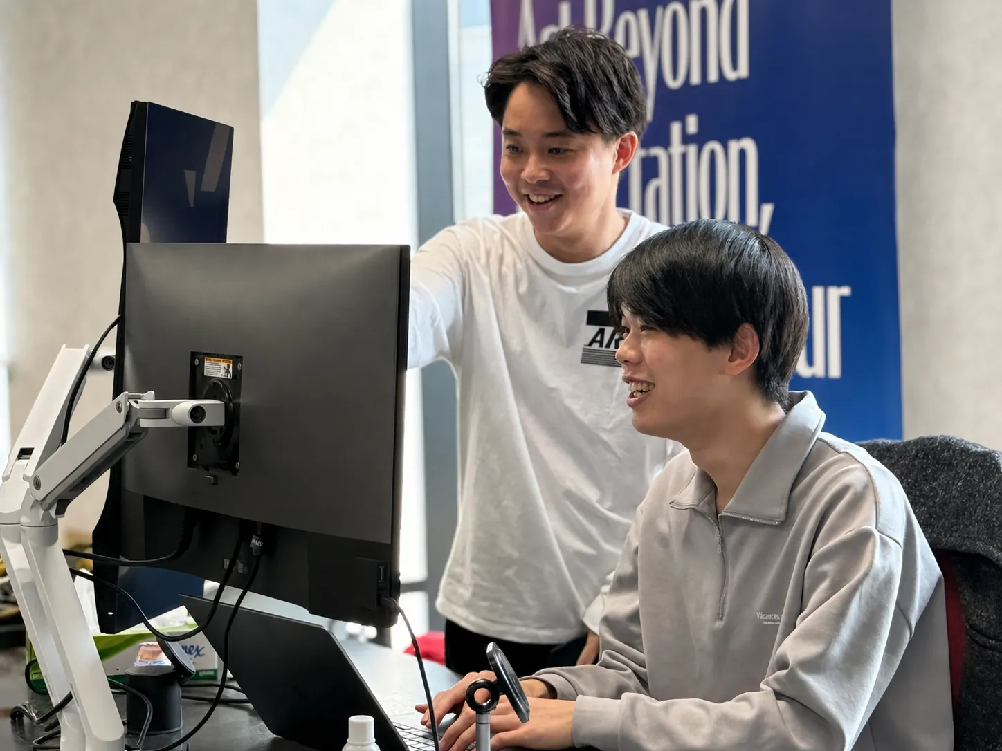 Two colleagues talking in front of a monitor