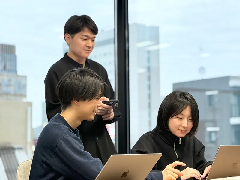 Colleagues looking at a phone by the window